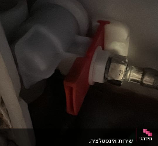 שסתום פלסטיק עם ידית אדומה בצנרת
